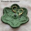 Fermoirs "dormeuses" posés sur une coupelle en métal verte en forme de fleur