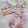 Boucles d'oreilles (fermoirs dormeuse plaqué or 24k) en résine colorée (rose, blanc et inclusion de feuilles d'or) composée d'un petit carré et d'un carré plus grand.